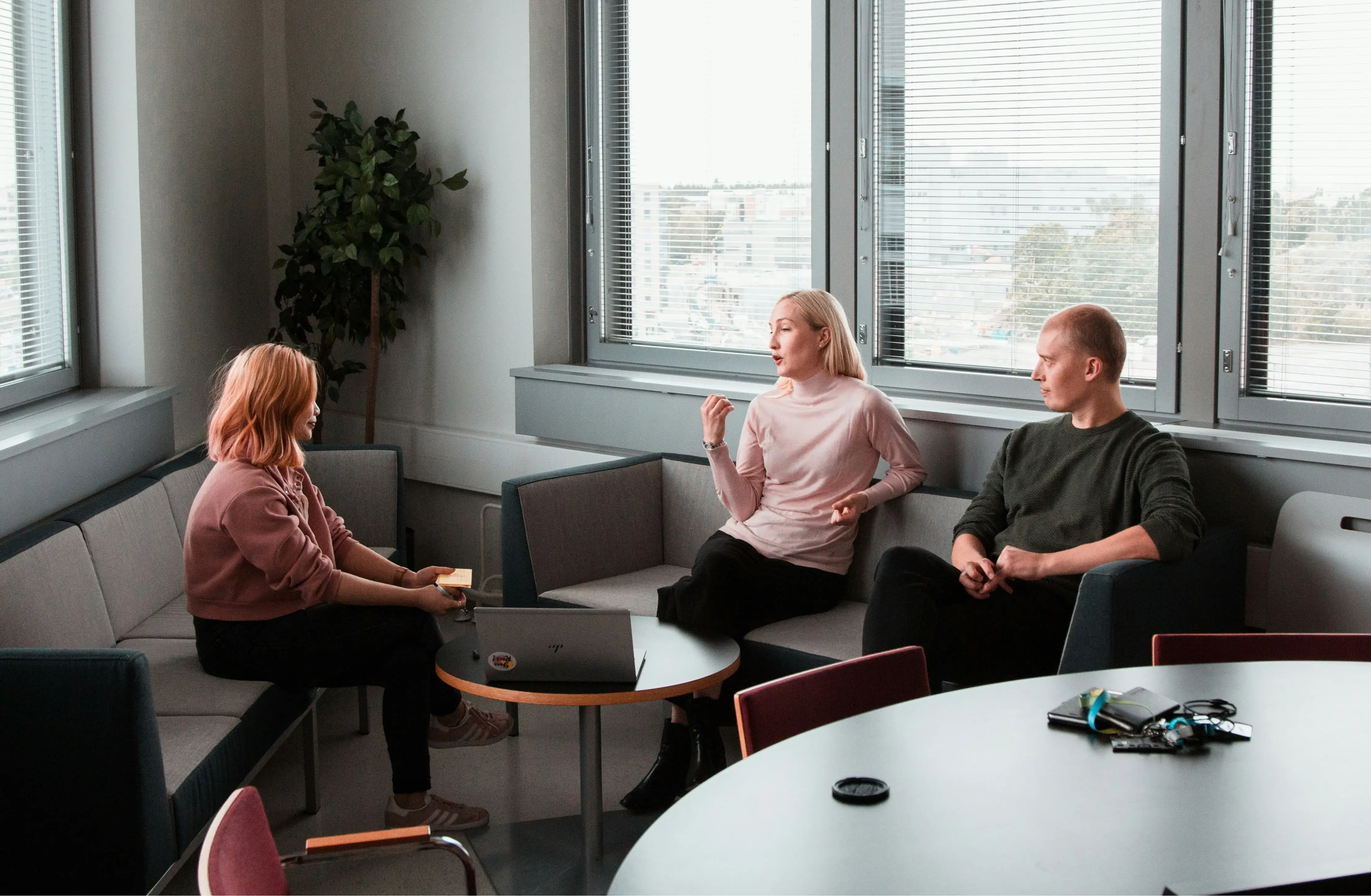 Drei Kollegen sitzen im Besprechungsraum zusammen und führen ein Mitarbeiter Feedback Gespräch im Team