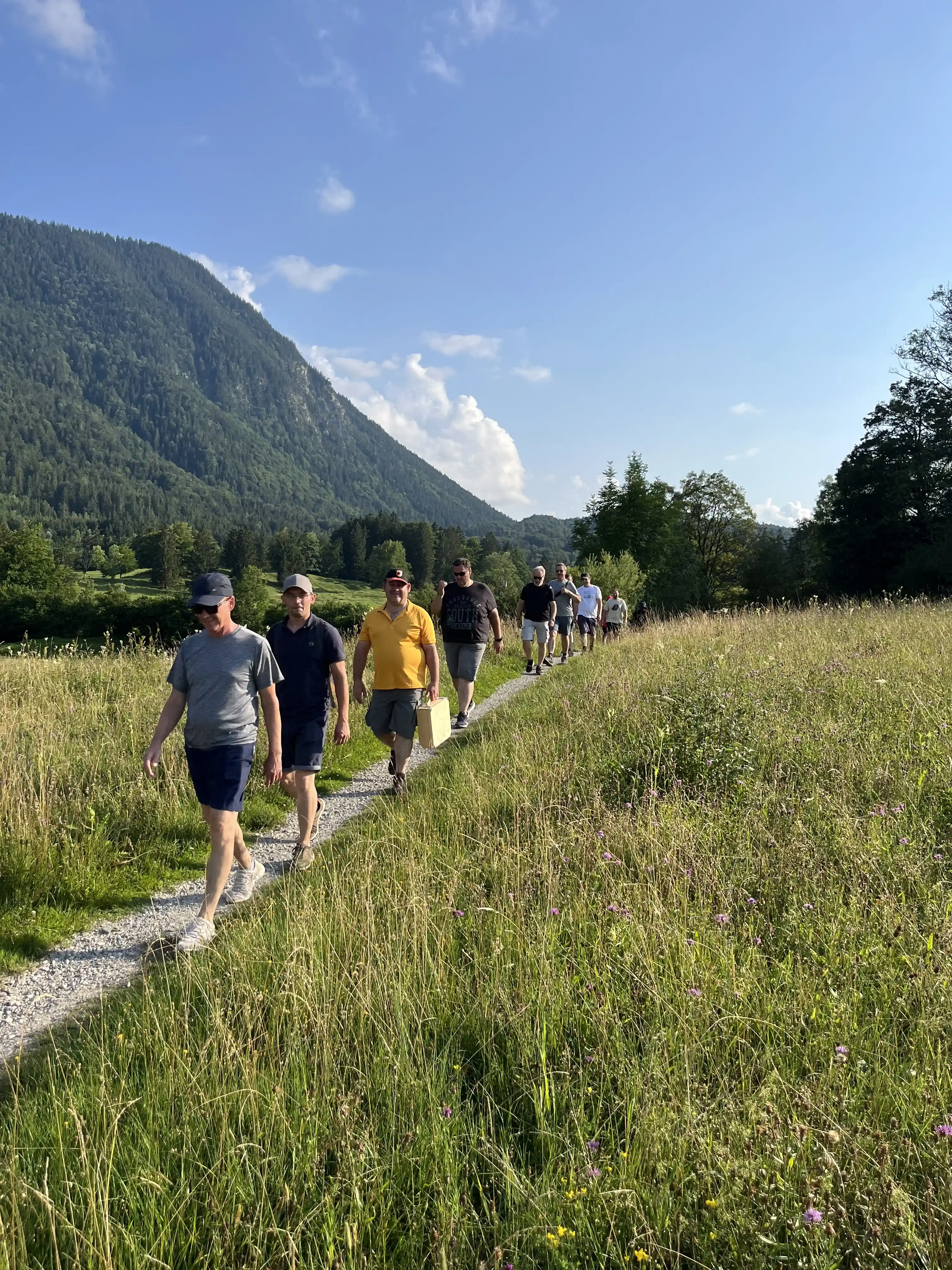Mitarbeiter laufen hintereinander einen Pfad durch die Berge entlang