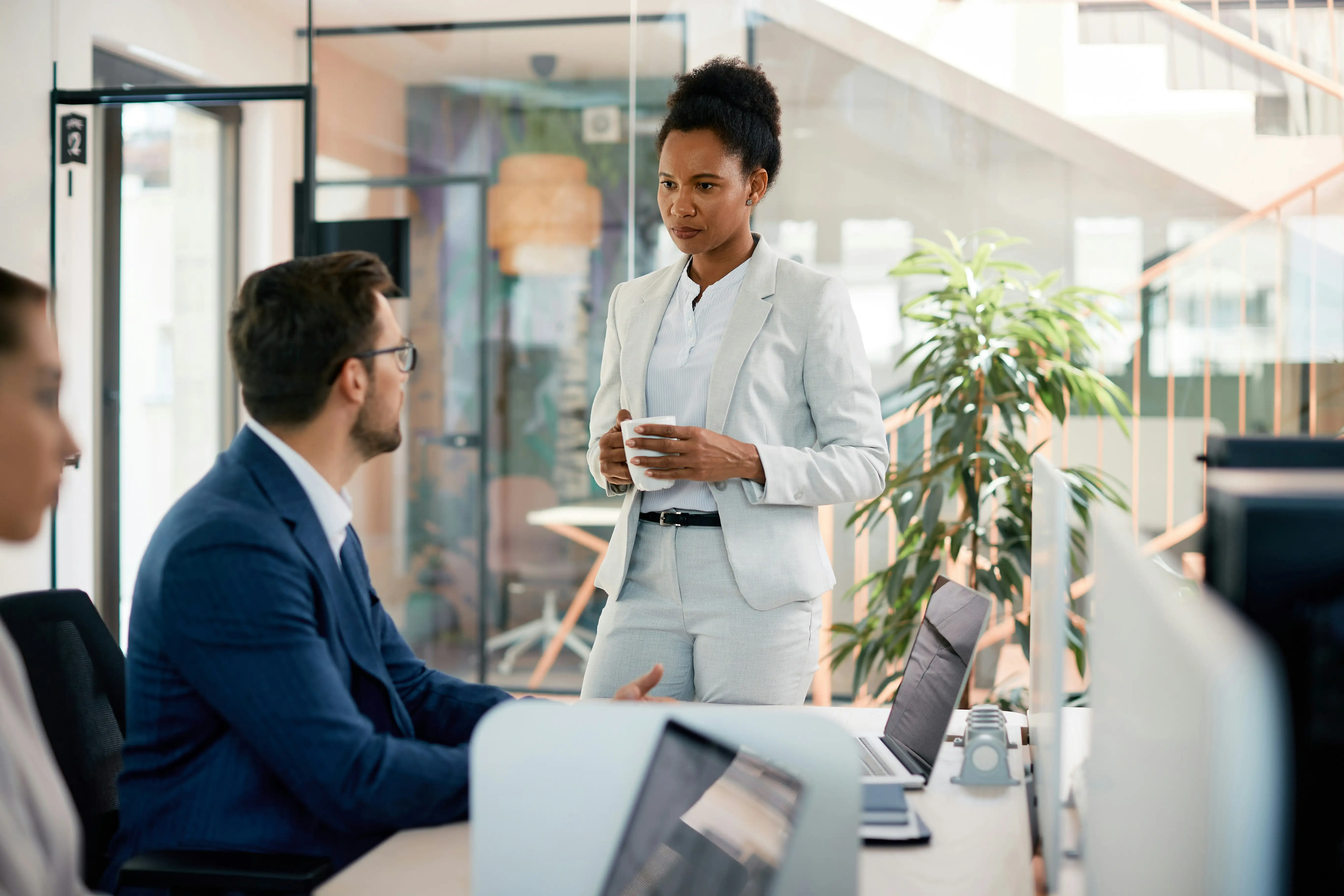 Mitarbeiterin spricht mit Kollegen am Schreibtisch