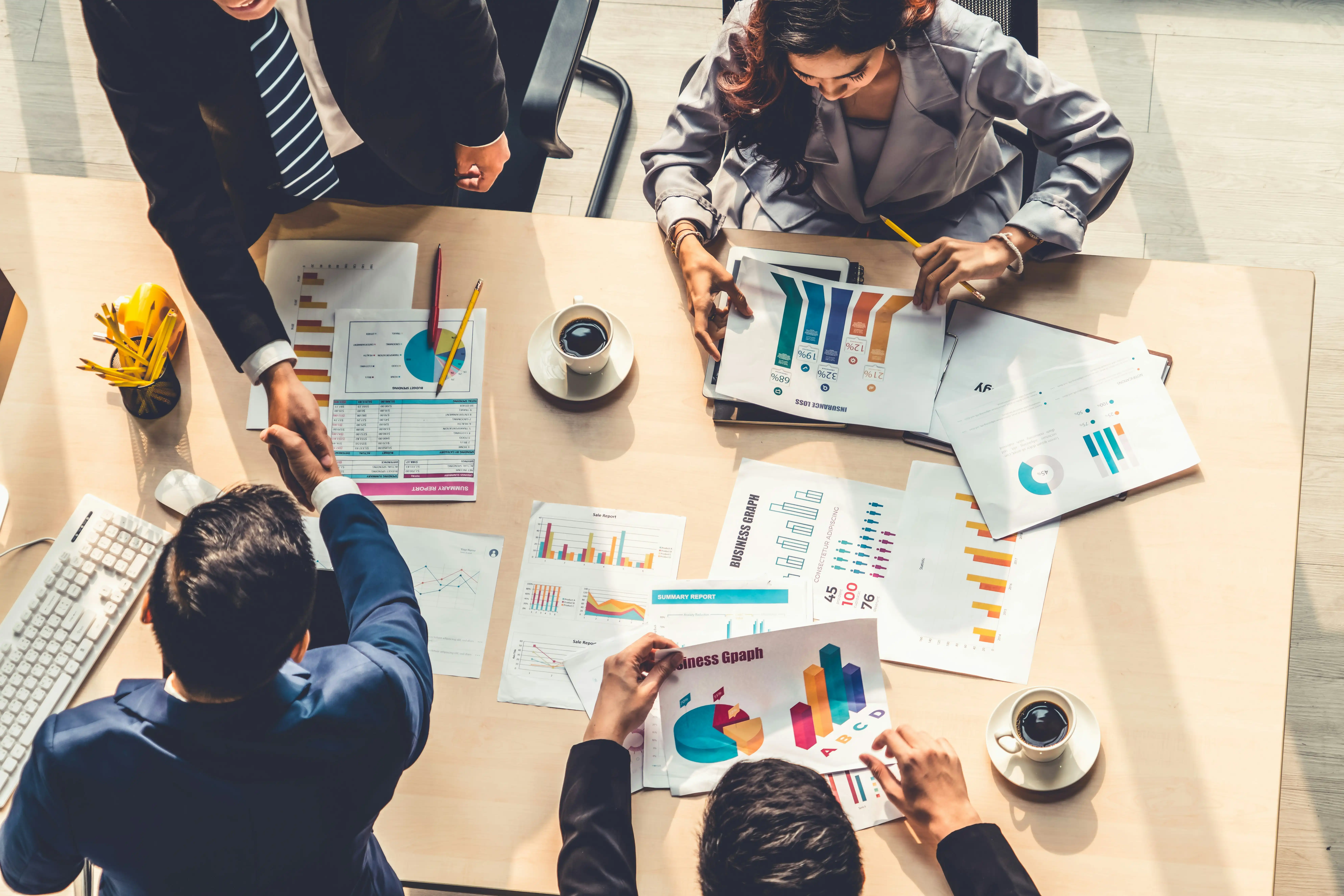 Mitarbeiter sitzen um Tisch voll mit Unterlagen und Graphiken