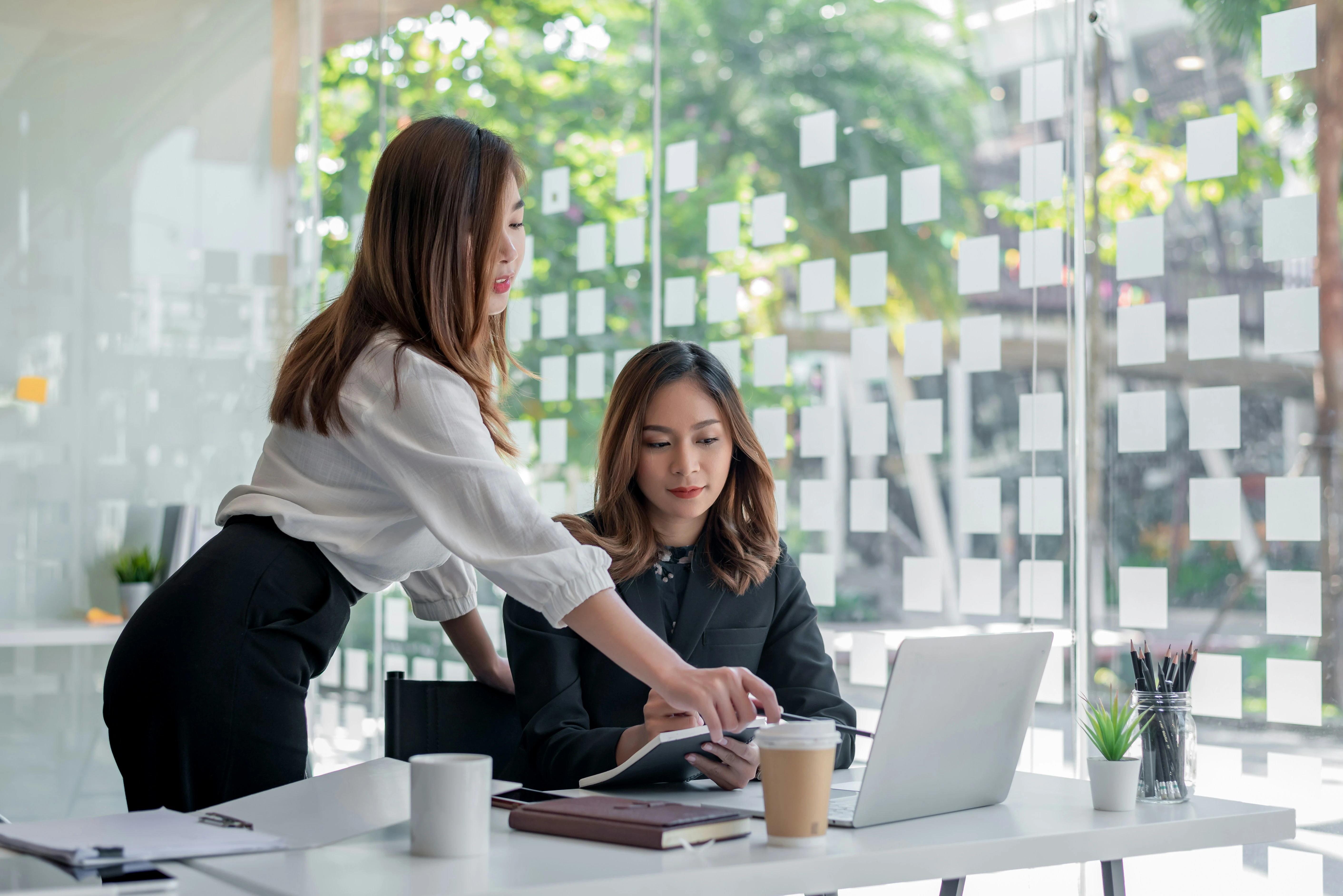 Mitarbeiterin zeigt Kollegin etwas auf Laptopbildschirm