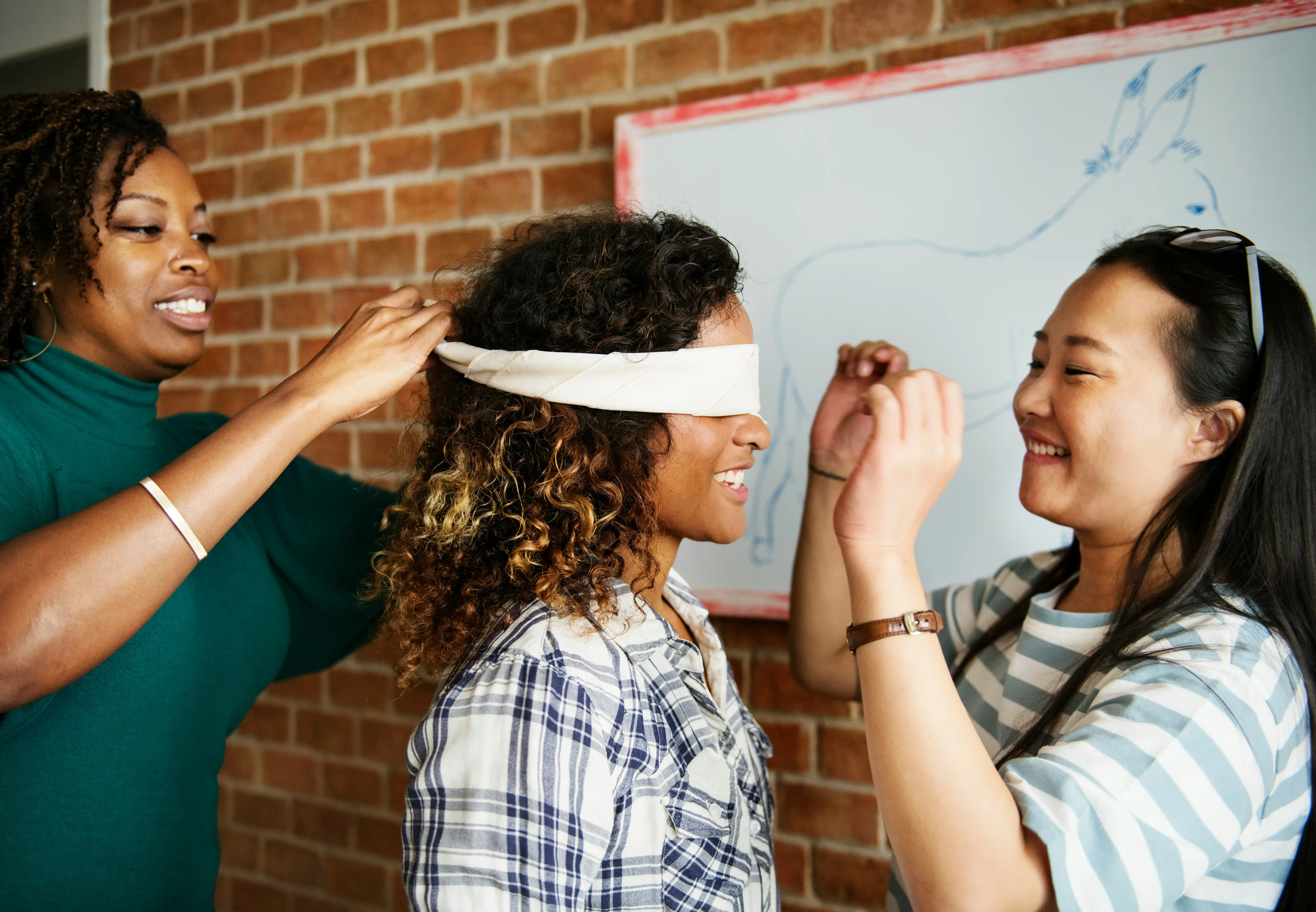 Kolleginnen verbinden Mitarbeiterin die Augen