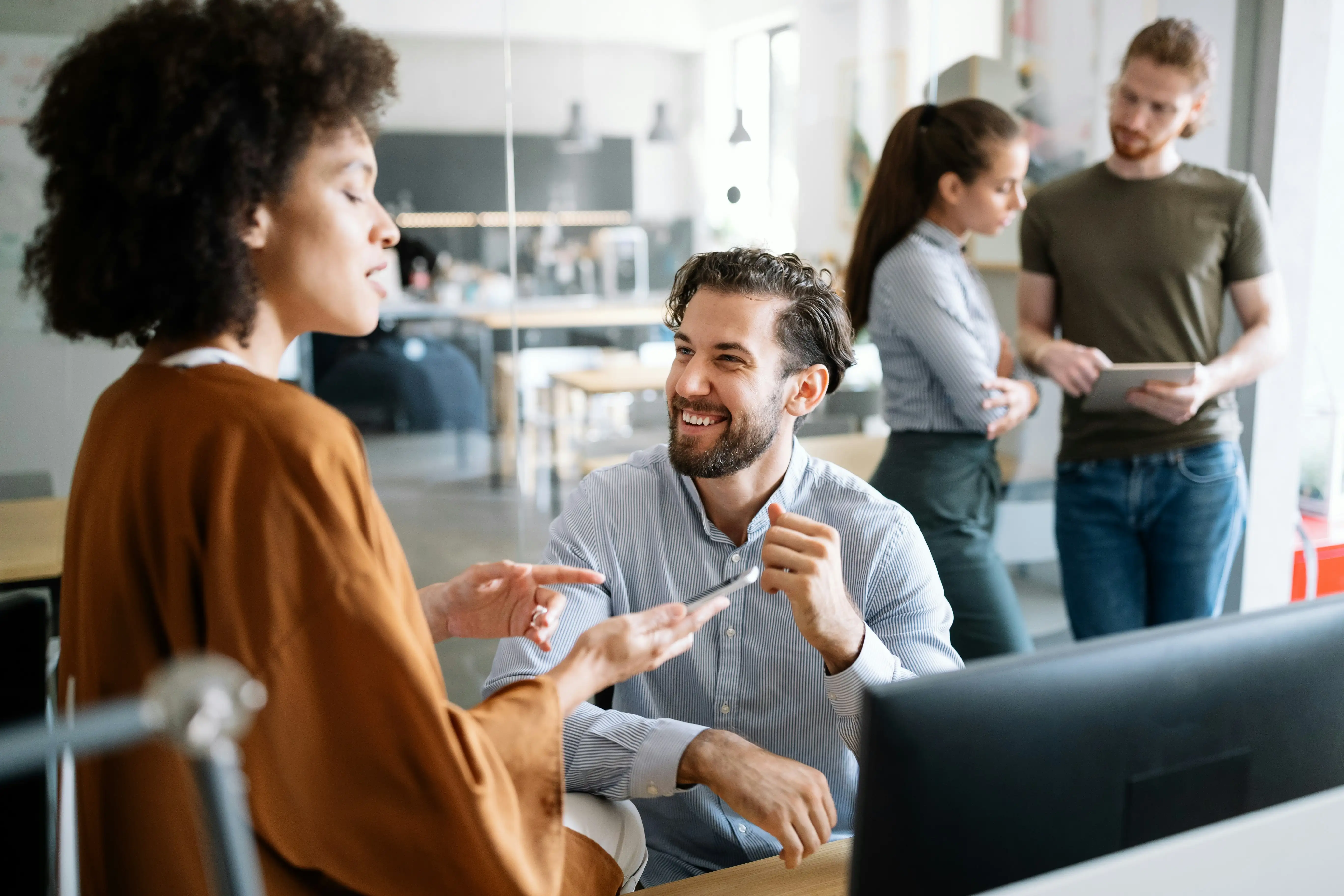 Kollegen unterhalten sich entspannt in 2er-Teams und reviewen die Arbeiten des anderen