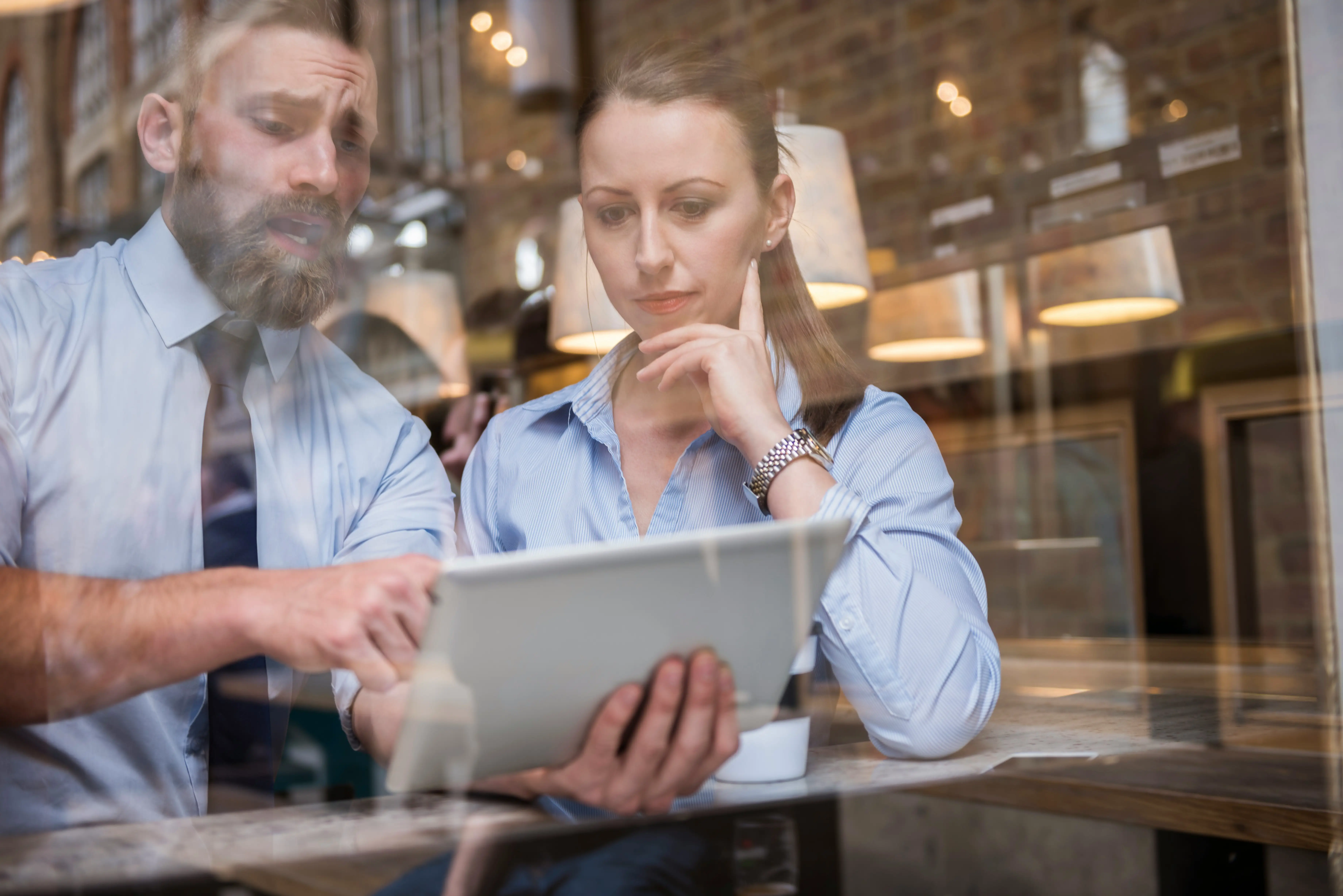 Zwei Kollegen schauen gemeinsam auf ein iPad und besprechen Projekte