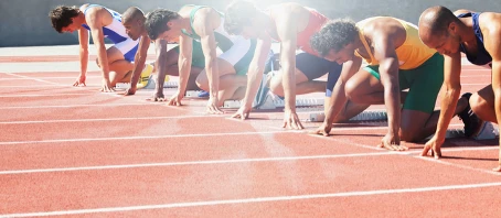 Läufer sind aufgereiht in Sprintposition an der Startlinie