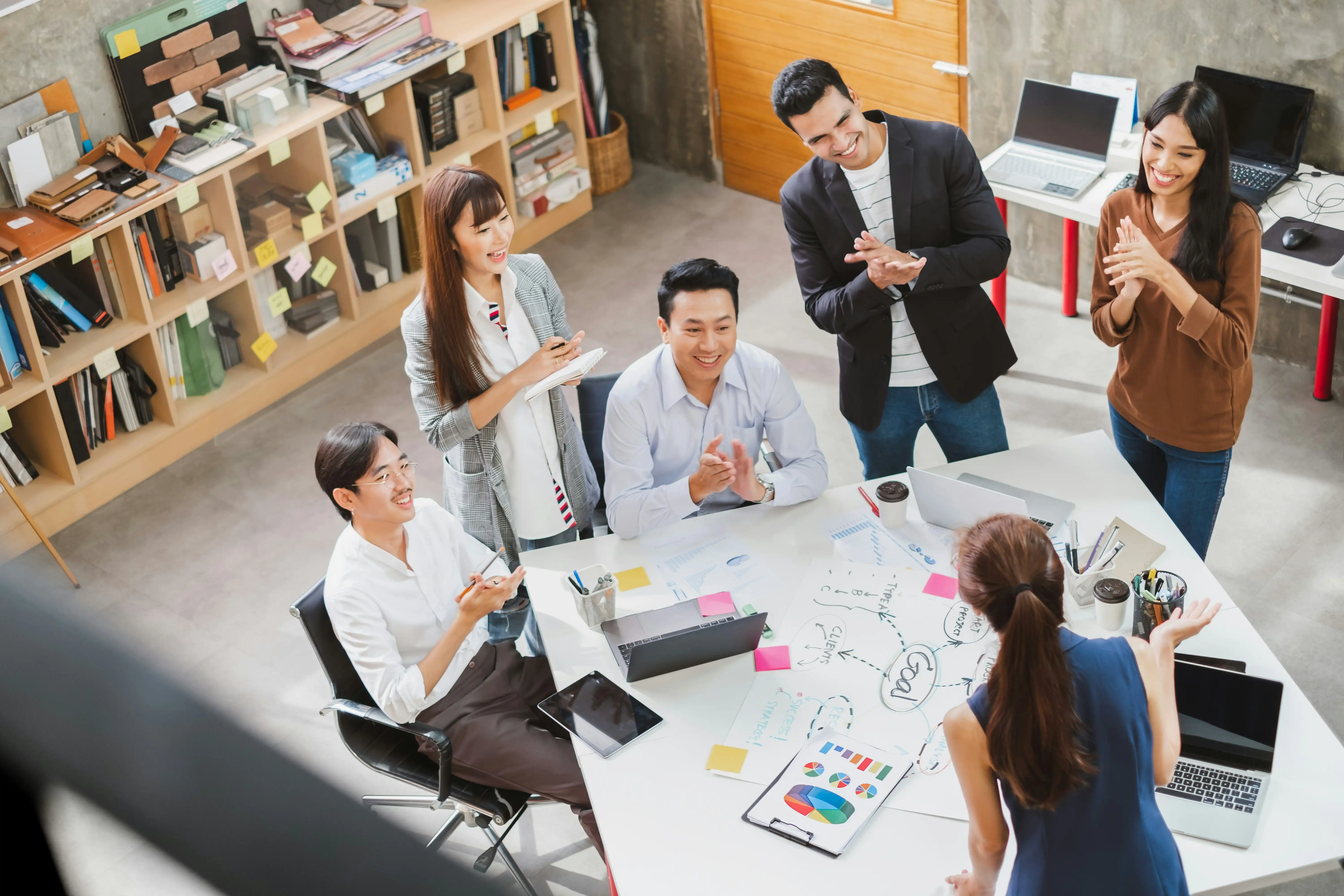 Teammitglieder hören Kollegin aufmerksam zu und applaudieren