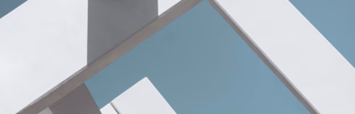 Close-up of a modern architectural structure featuring clean white beams and columns against a clear blue sky, showcasing minimalistic design.