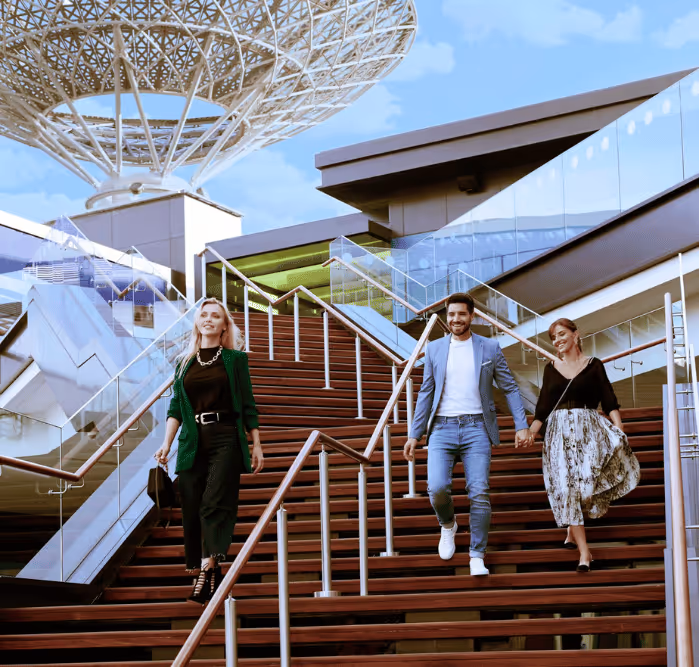 Three friends walking down wide outdoor steps at Bluewaters Island with the distinctive canopy structures above them.