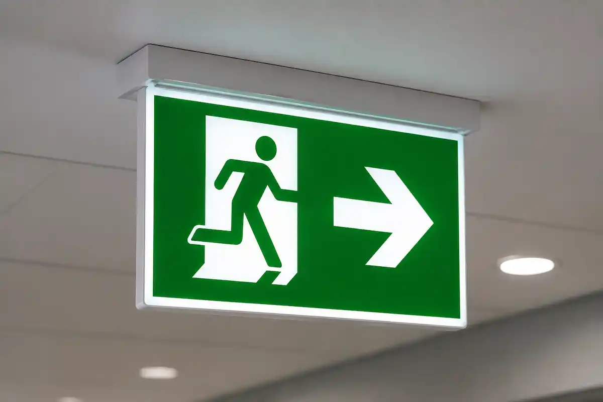 Green emergency exit sign with a running figure and a right-pointing arrow.