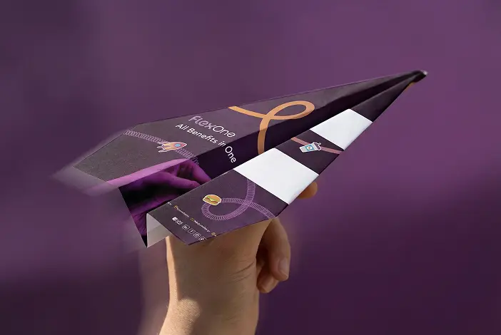 Χέρι που κρατά ένα χαρταετό με μοβ φόντο και το κείμενο 'FlexOne All Benefits in One'.