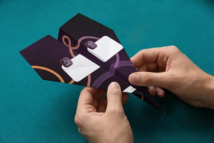 Άνθρωπος που διπλώνει αυτοσχέδιο αεροπλάνο από χαρτί με μοτίβα και σύμβολα.