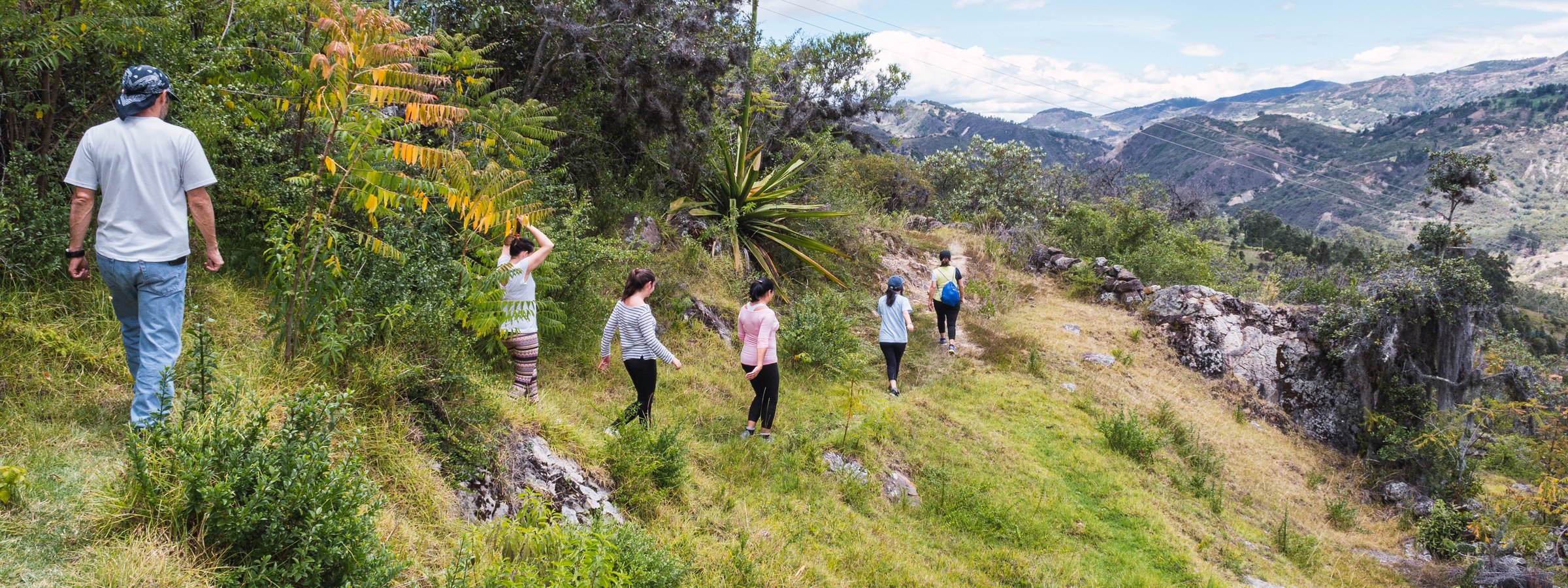 Un acompañante y un grupo de viajeros caminando por un sendero en los Andes