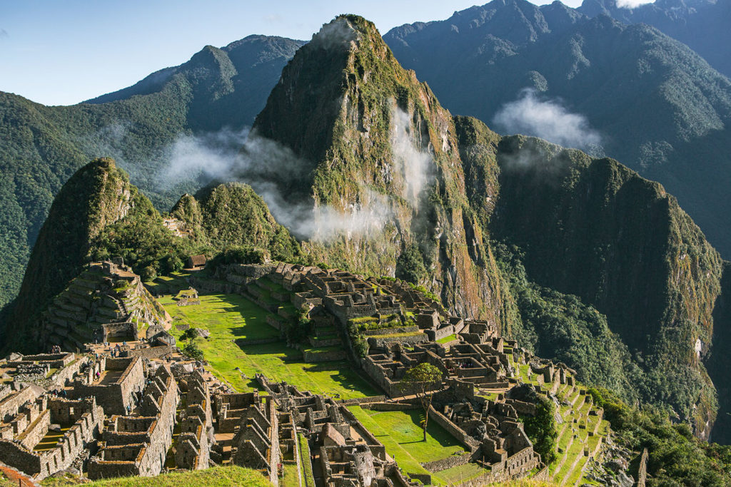 Vue panoramique du Machu Picchu au lever du soleil, citadelle inca entourée de montagnes verdoyantes et de brume andine.