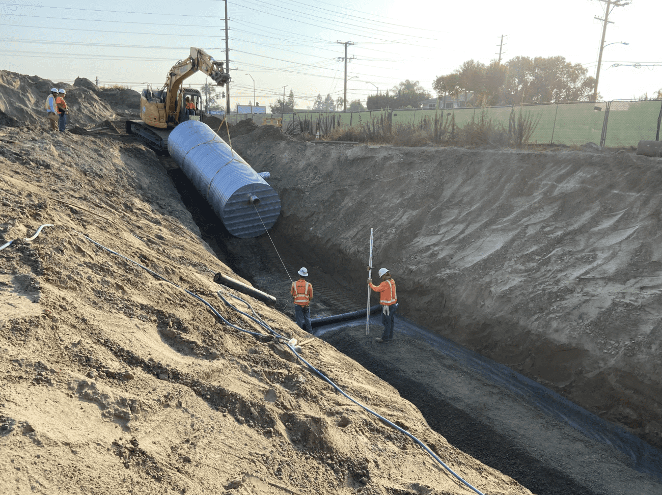 Worker inspecting alignment of stormwater or sewer pipeline during trench excavation.