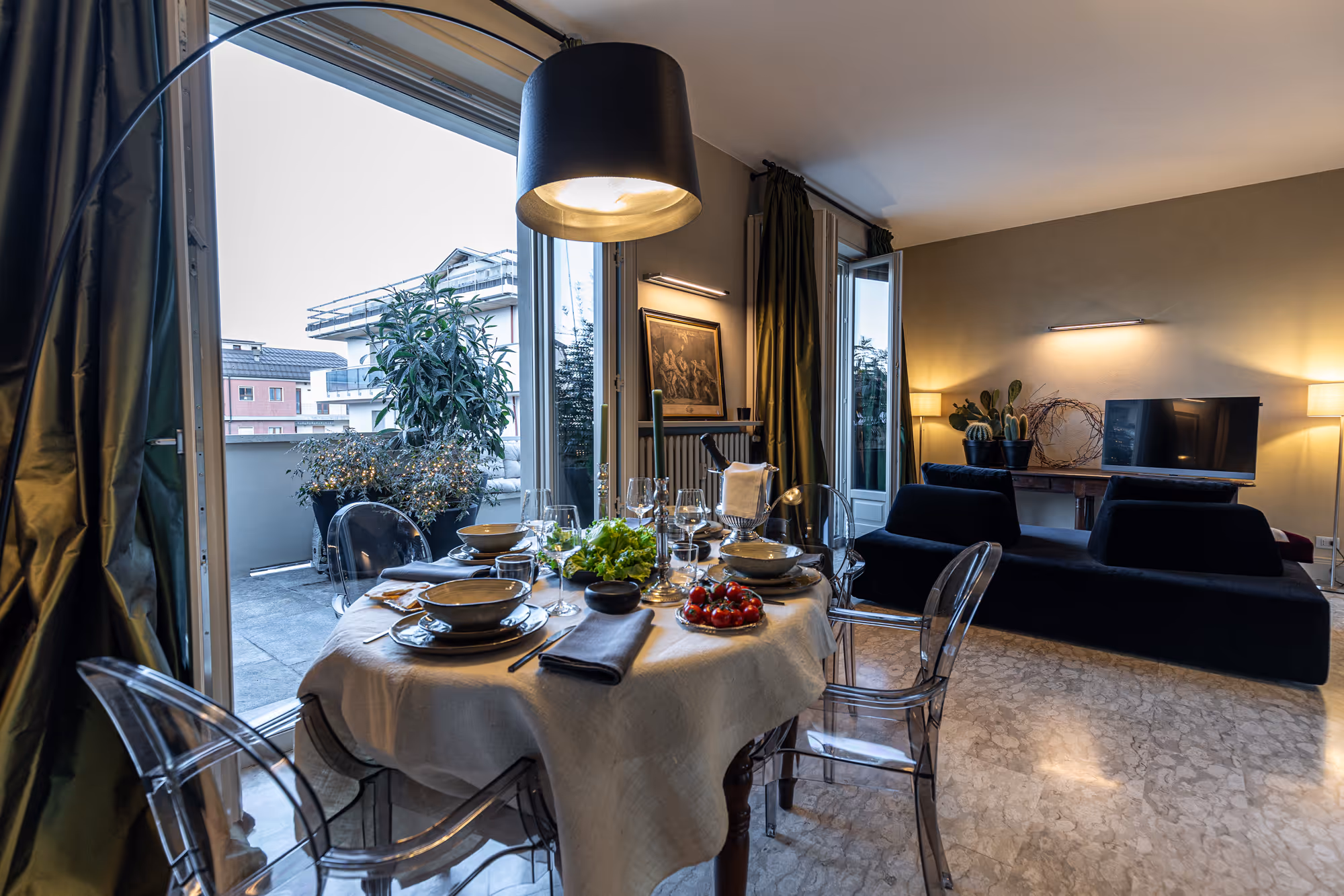 Elegante sala da pranzo moderna con tavolo apparecchiato, lampadario nero e accesso a terrazza esterna.