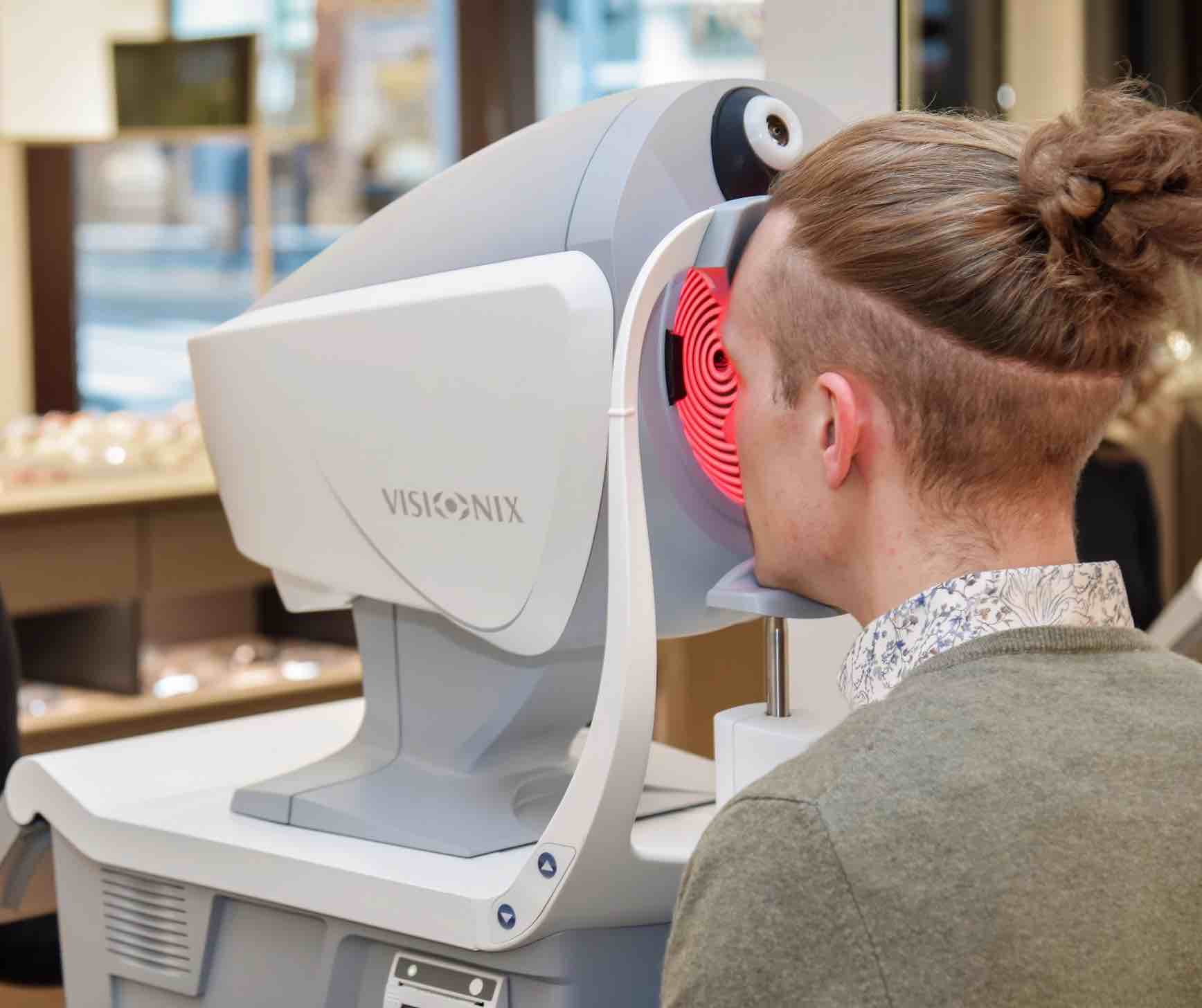 Ein junger Mann wird bei Optik Hess mit einem tipmodernen Visionix untersucht.