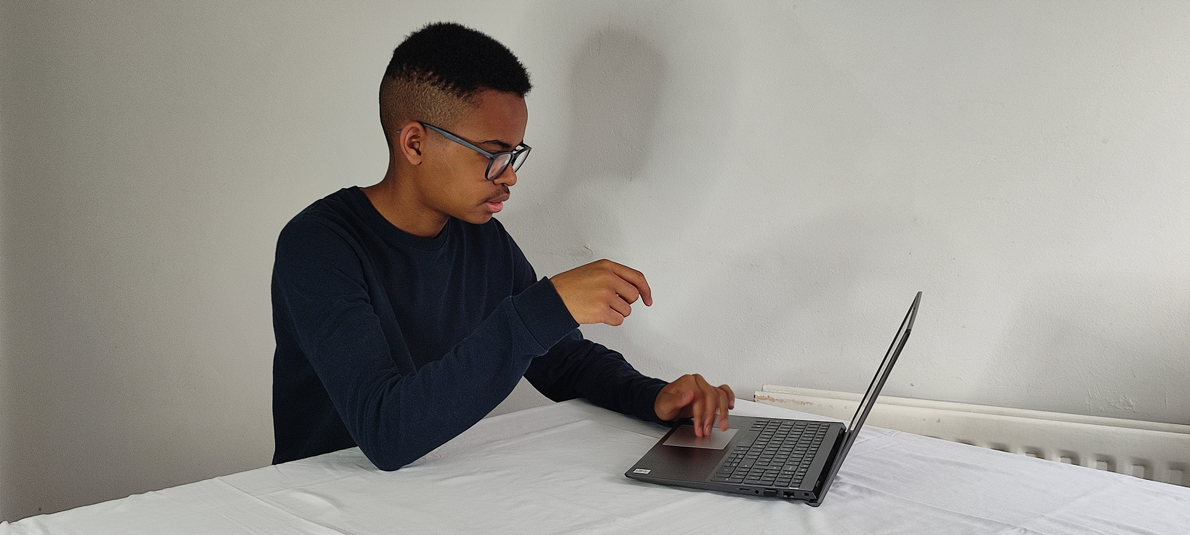 Elijah Mbale using a laptop on a desk to design websites.
