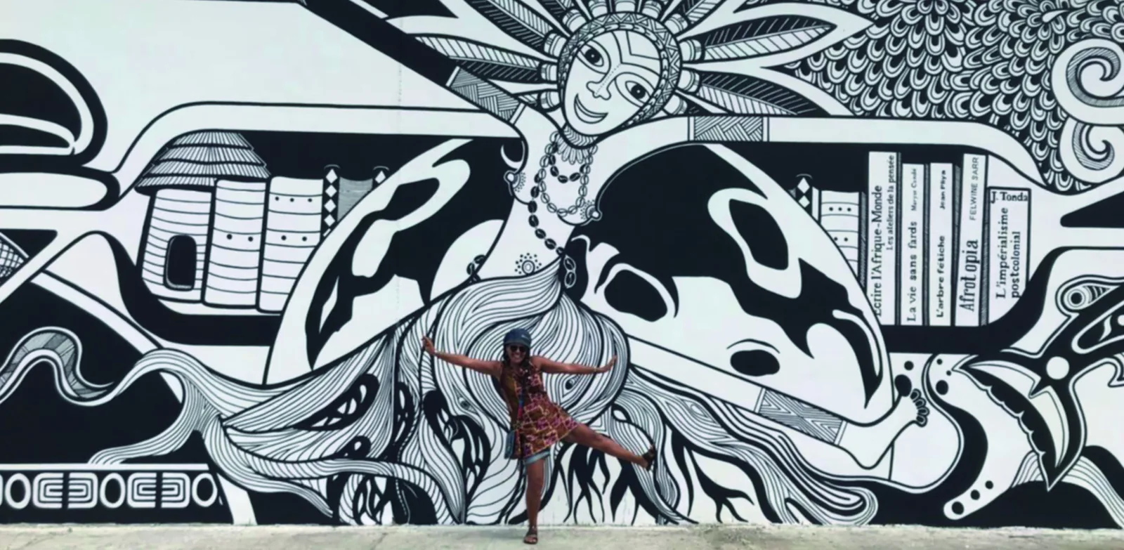 Afi Kodjobi devant sa fresque en noir et blanc