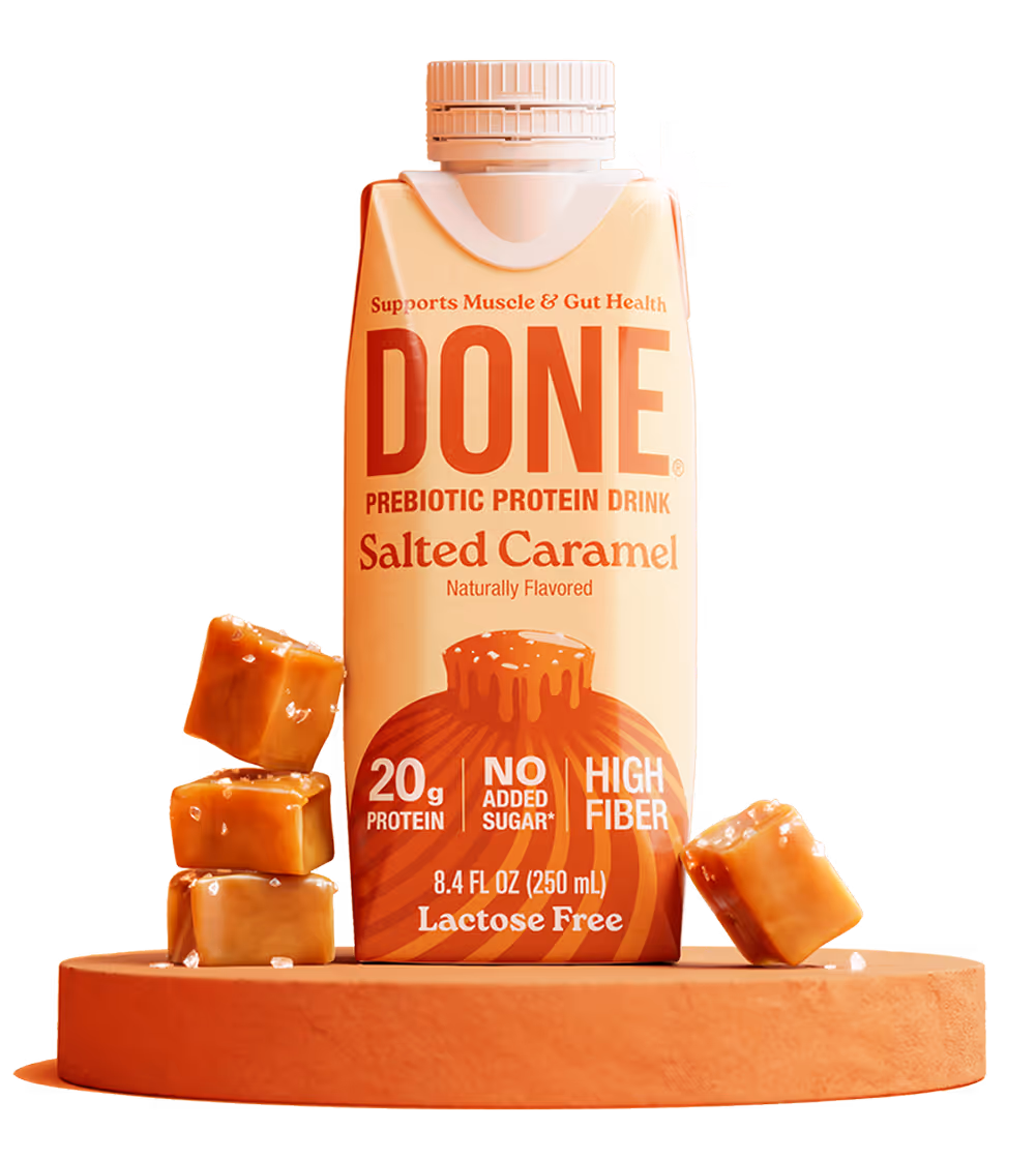 DONE Drinks Salted Caramel protein shake standing on a round orange pedestal with caramel pieces.
