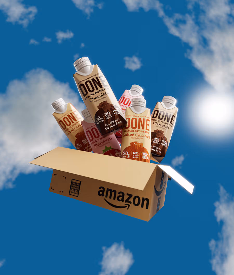 Amazon box with several DONE prebiotic protein drink cartons in flavors chocolate, salted caramel, and strawberry floating against a blue sky with clouds.