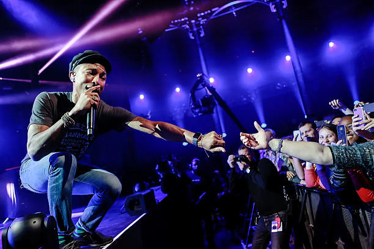 Pharell Williams reaches out to an audience member whilst performing.