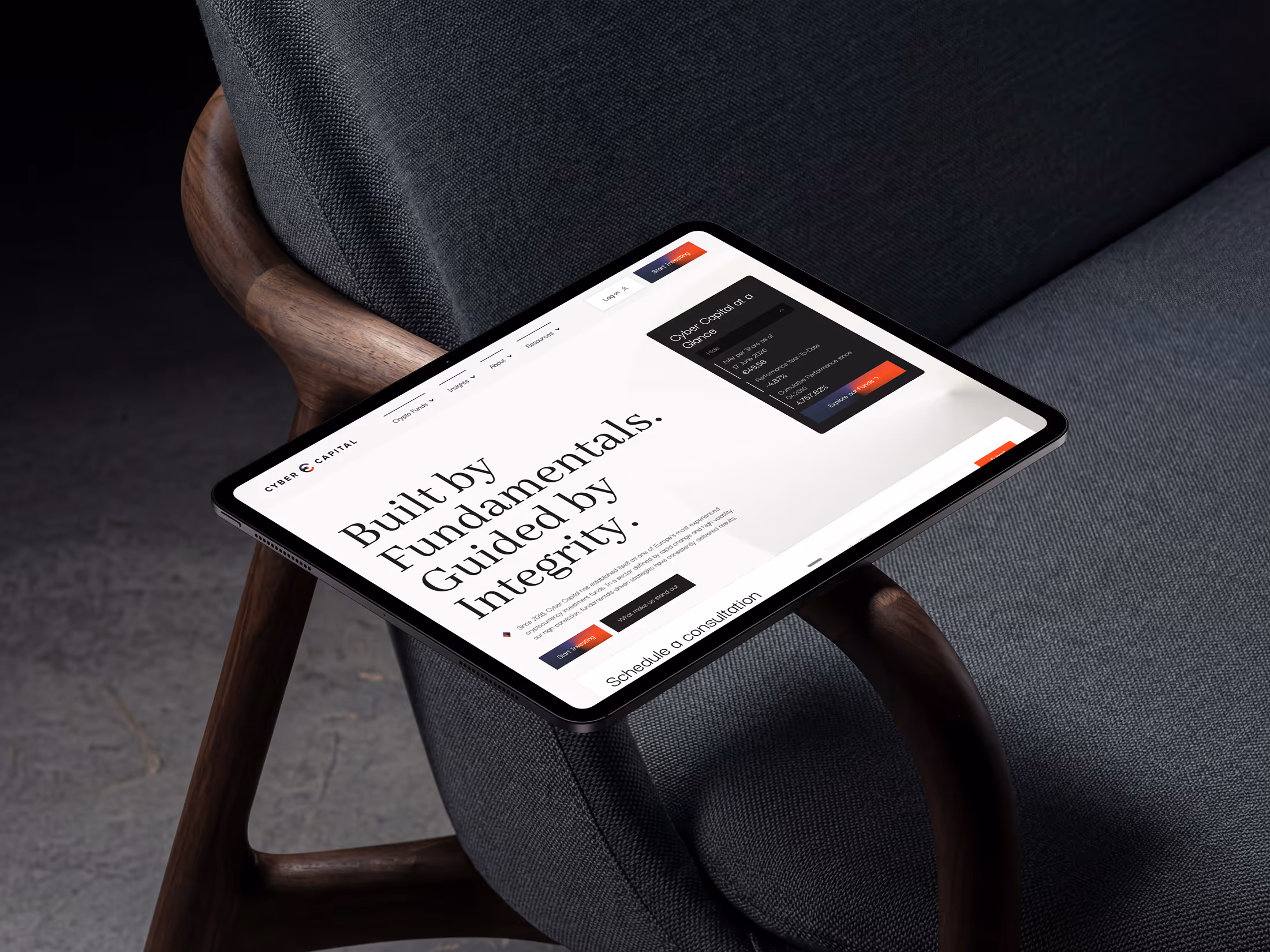Tablet on a gray fabric chair displaying a website with 'Built by Fundamentals. Guided by Integrity.'