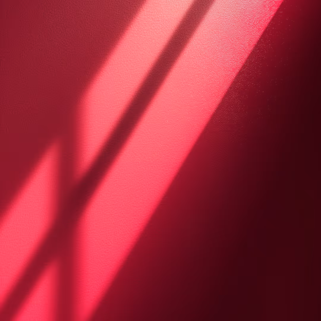 Red wall with sunlight casting diagonal shadows creating varying shades of red.