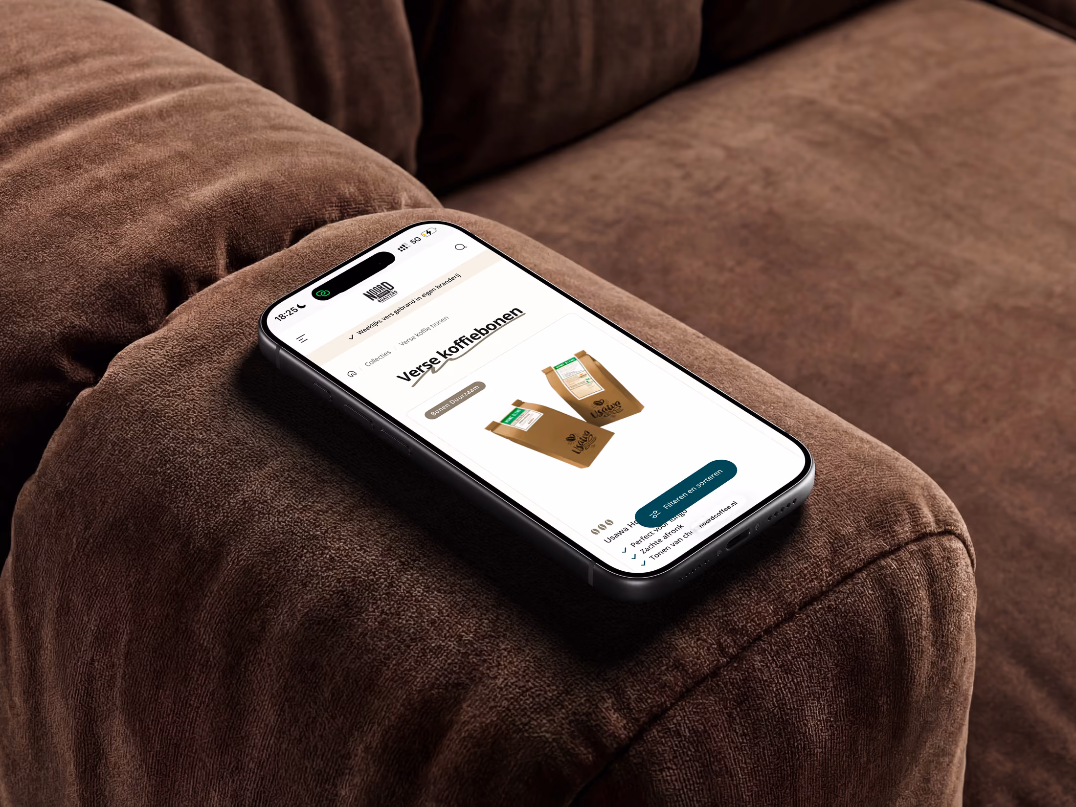 Smartphone on brown sofa showing a webpage with fresh coffee bean packages.