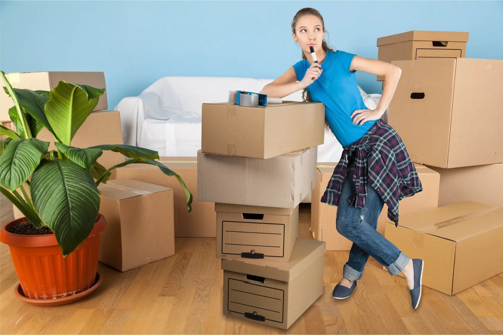 Smiling young woman standing beside packed boxes, excited to move out of her family home