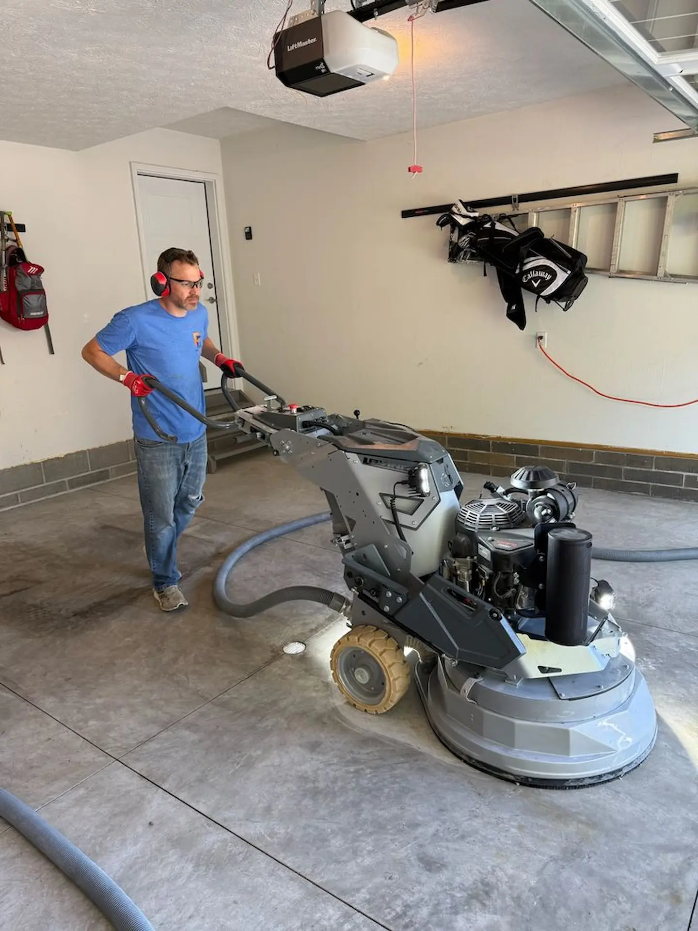 Dan from Poly Guys using a concrete grinder before coating the garage floor