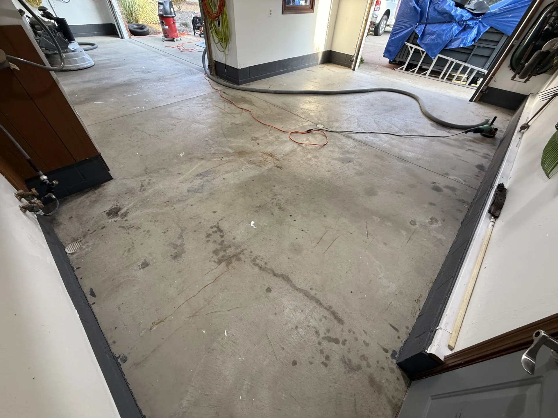 Garage concrete floor before coating, showing surface wear and staining near the entry.