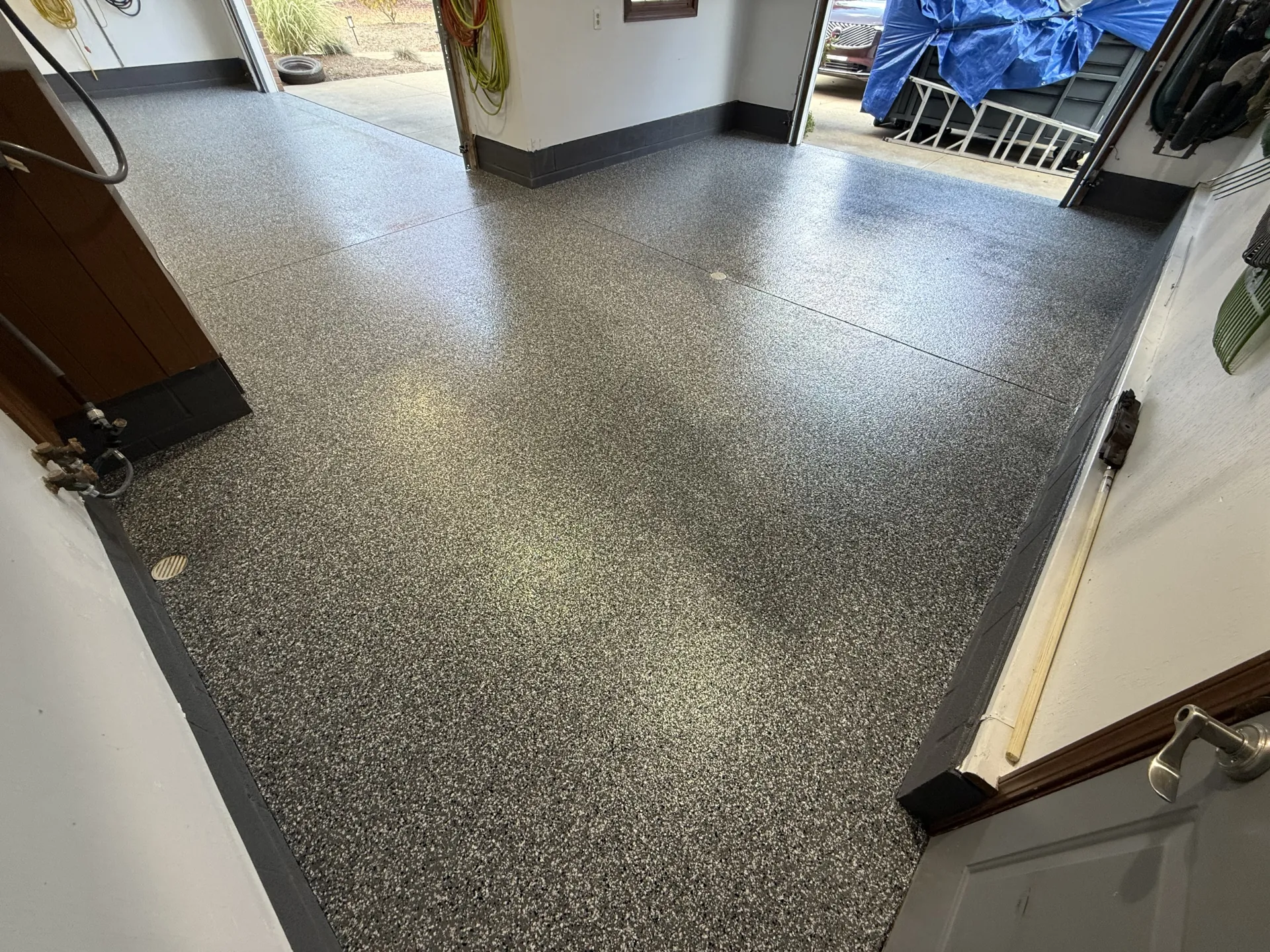 Finished garage floor after coating, glossy Driftwood flake finish with control joints visible.