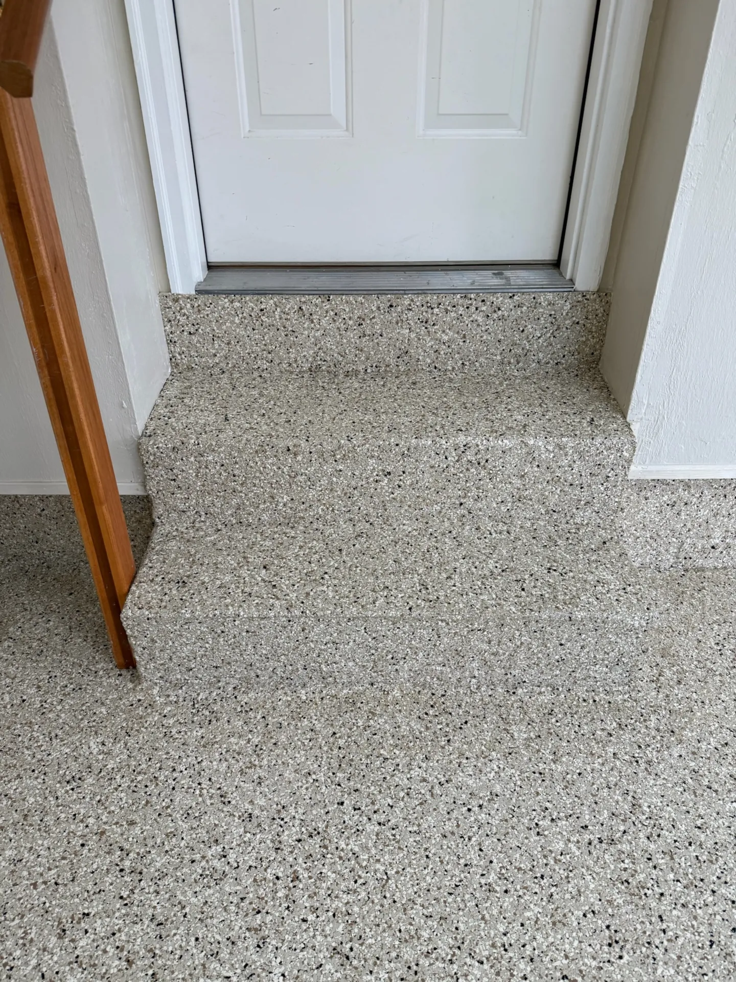 Close-up of coated garage steps and landing with matching light flake finish at the entry door.