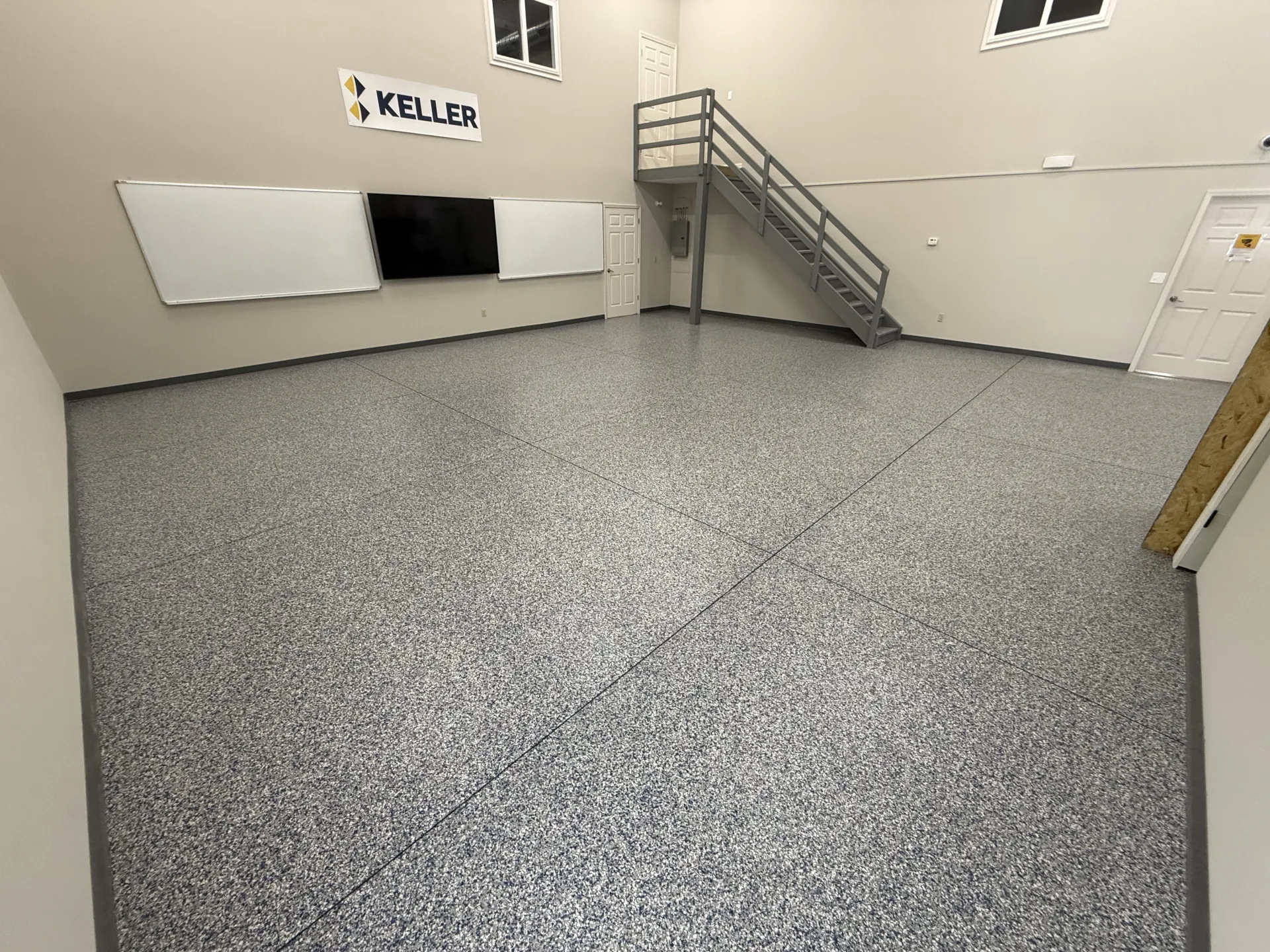 Custom polyaspartic flake floor installed at Keller Construction conference room and warehouse space, featuring a seamless gray custom flake blend with a durable commercial-grade finish.
