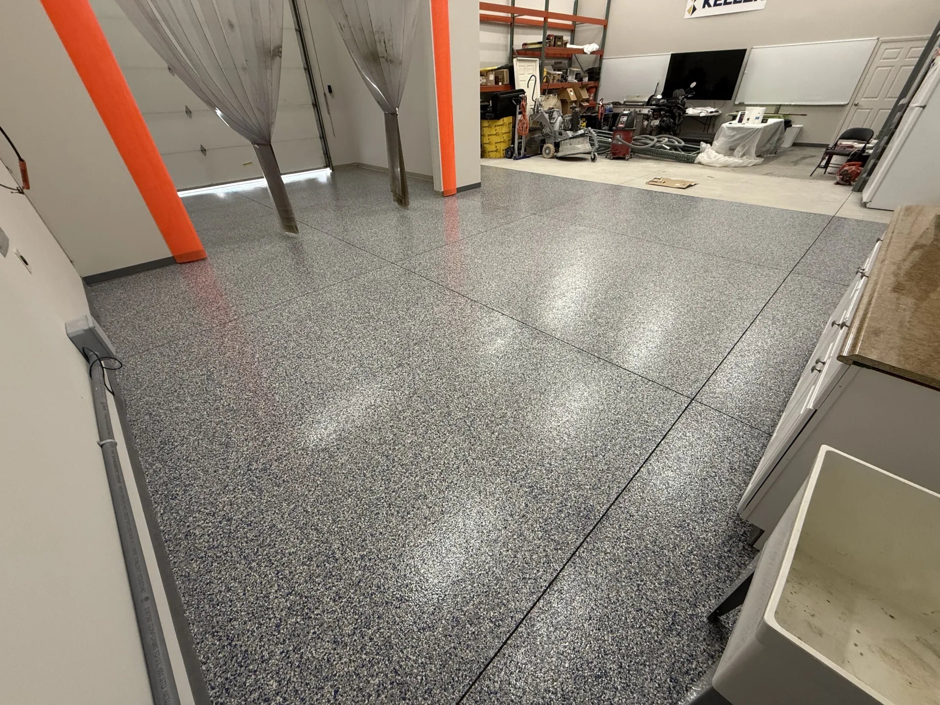 Newly installed polyaspartic flake flooring at Keller Construction warehouse, showcasing a custom gray flake system with a clean, slip-resistant, high-performance surface.