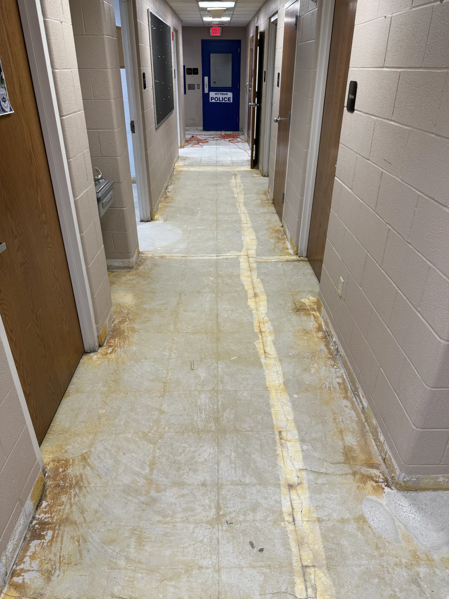 Existing concrete hallway floor after repairs and preparation, showing the surface ready for installation of a polyaspartic flake floor coating in a commercial facility.