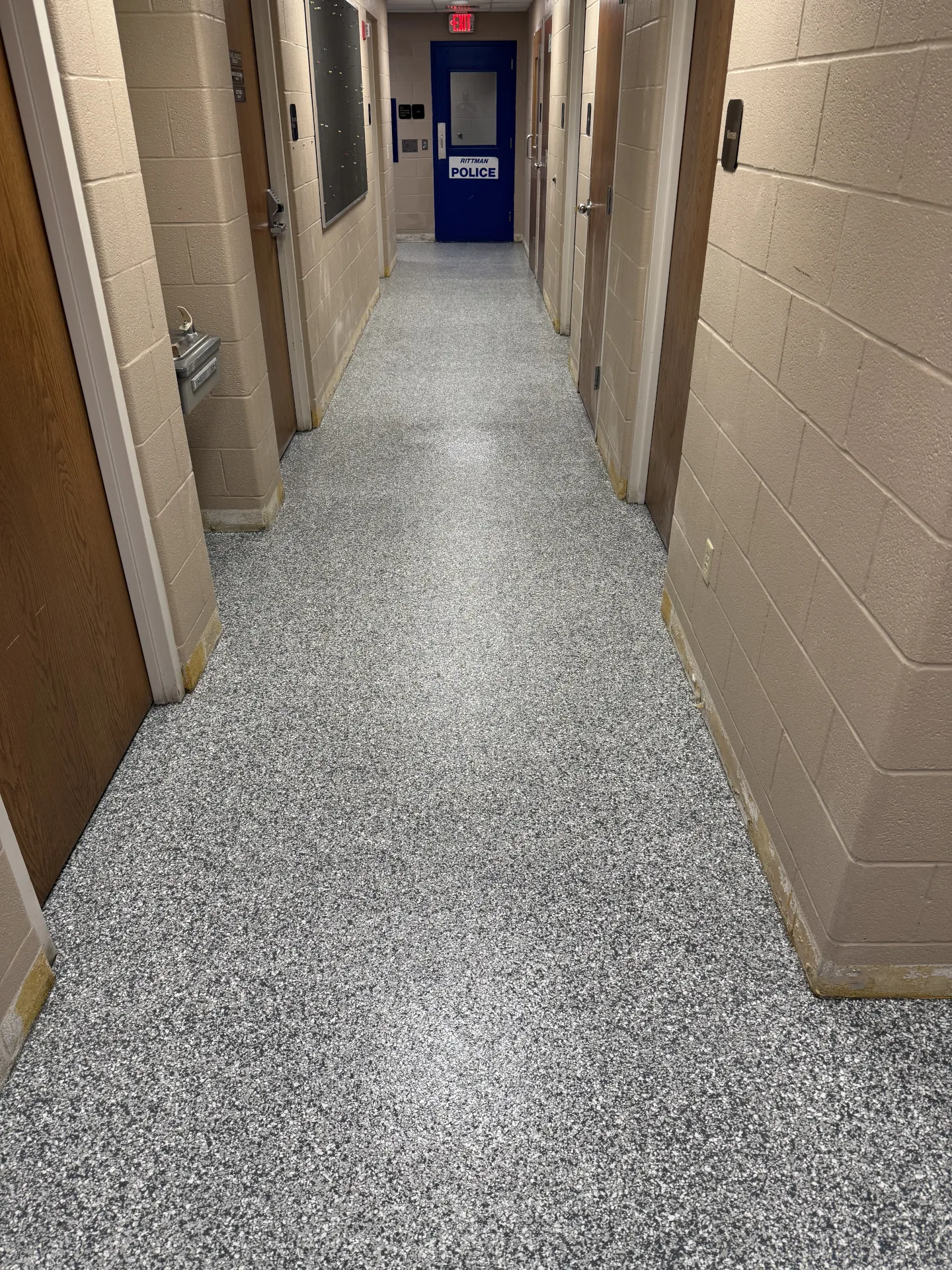 Finished polyaspartic flake flooring installed in a police department hallway, featuring a decorative gray flake system designed for high-traffic commercial use.