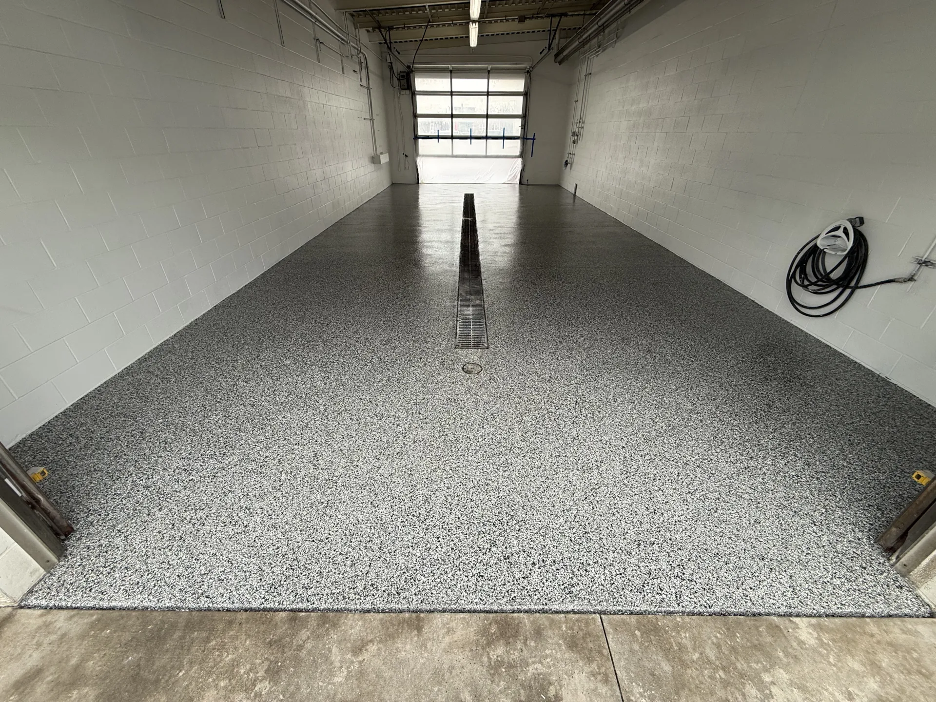 Newly installed commercial polyaspartic flake flooring in a vehicle wash bay, providing a durable, slip-resistant surface designed for heavy traffic, water exposure, and daily use.