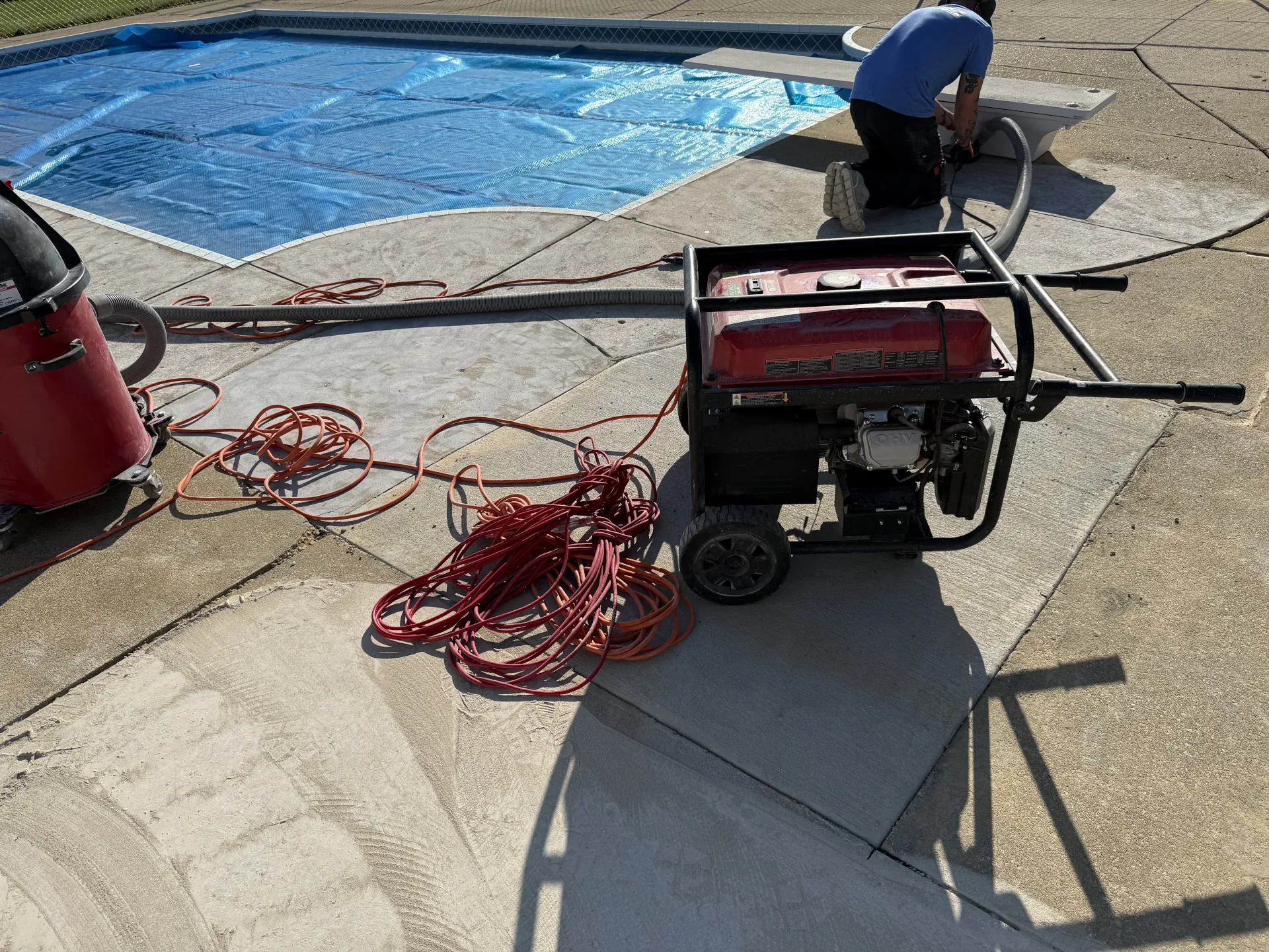 Poly Guys technician performing concrete grinding and surface preparation around a swimming pool deck before installation of an outdoor polyaspartic flake coating system.