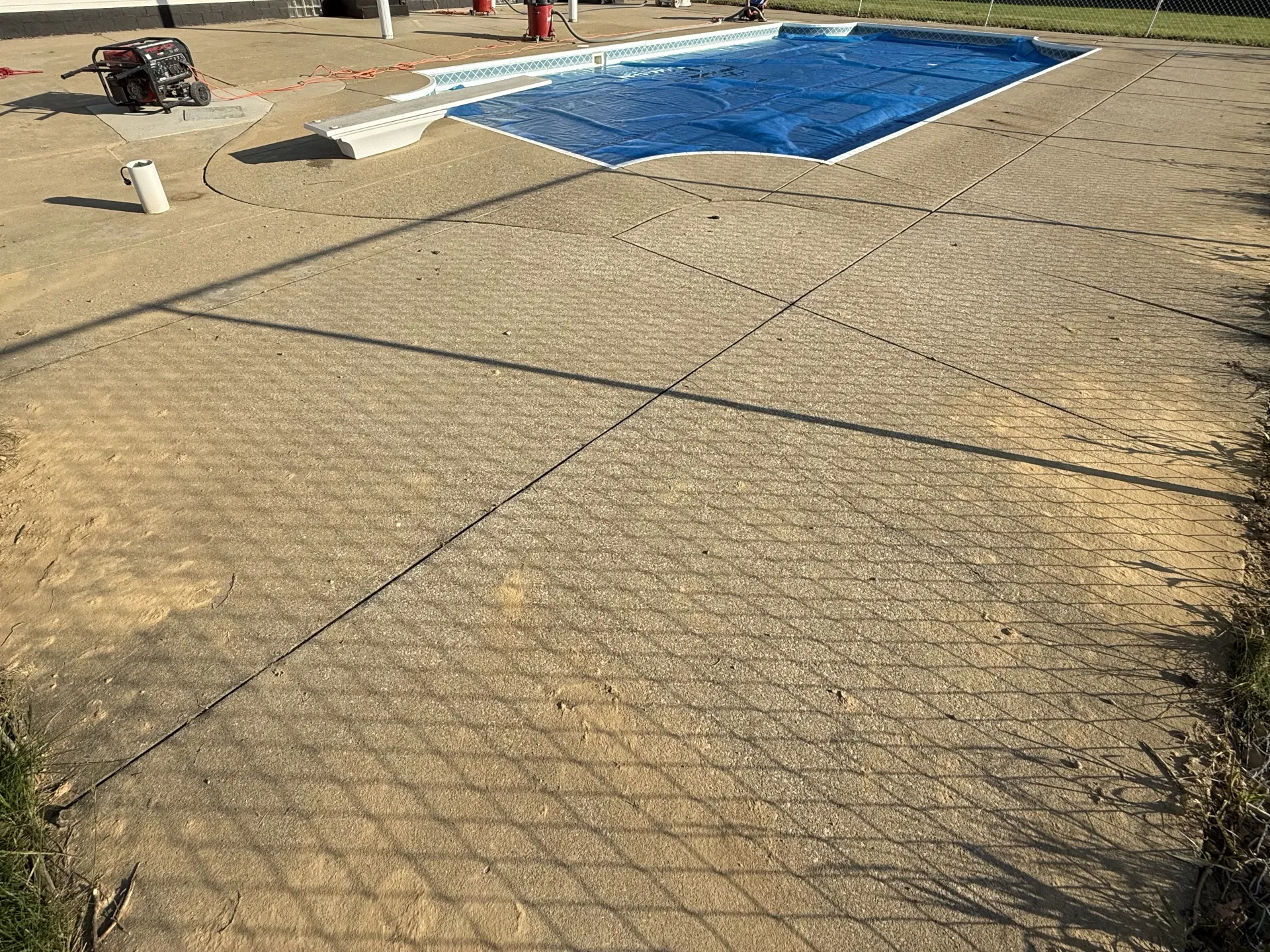 Existing concrete pool deck before coating installation, showing weathered concrete surface surrounding an in-ground swimming pool prior to preparation and restoration.