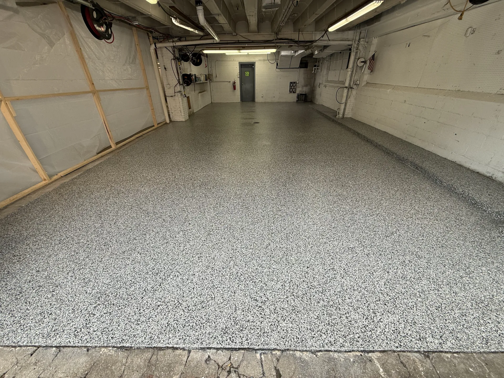 Completed commercial polyaspartic flake floor coating featuring a gray and white decorative flake blend, creating a seamless, durable, and professional-looking workspace.