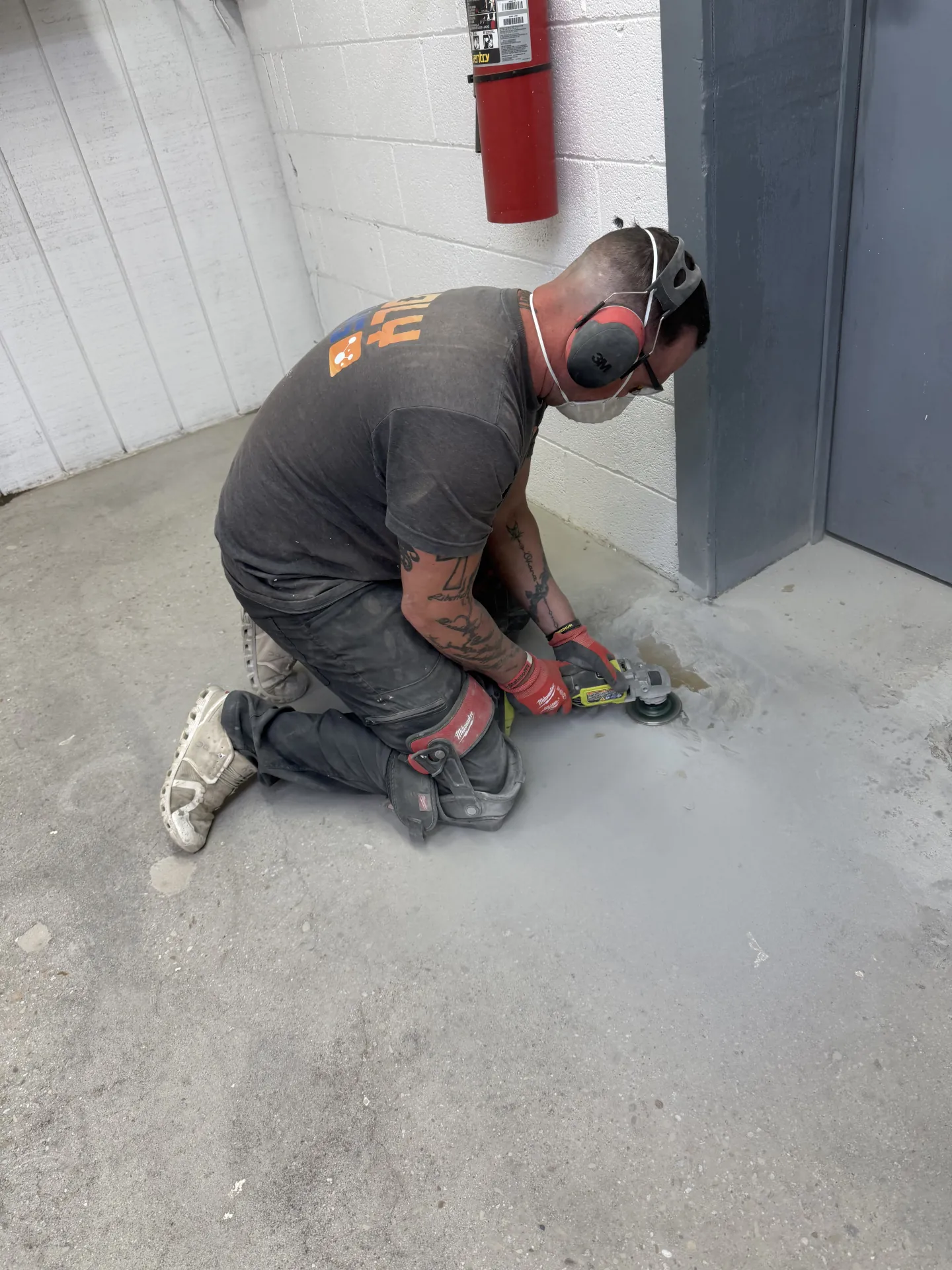Poly Guys technician performing detailed edge grinding around door frames and walls to ensure proper surface preparation before installing a commercial floor coating system.