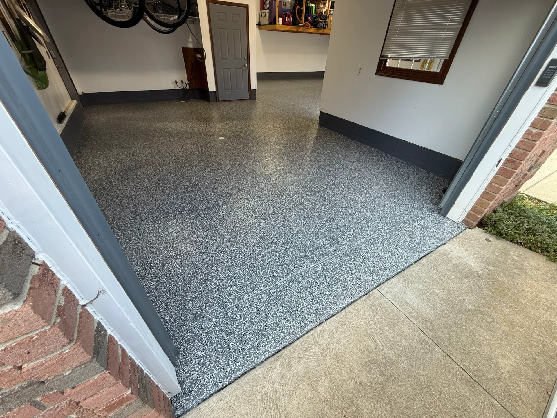 Polyaspartic garage floor coating with a gray decorative flake finish in a residential garage.