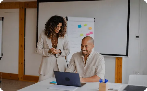 Two colleagues collaborating on a laptop during a professional office meeting