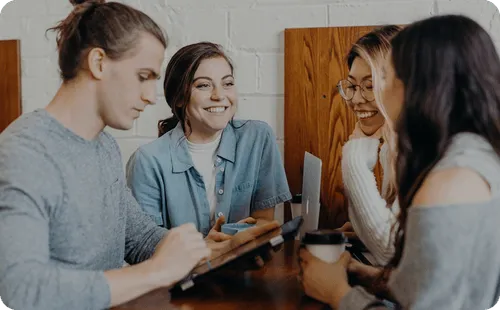 Small team collaborating around a table while reviewing content on a tablet