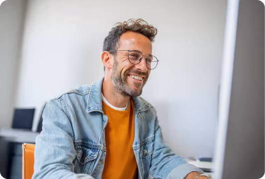 Sales professional smiling while working on a laptop in a modern office