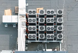 A group of air conditioning fans on the rood of a large industrial building.