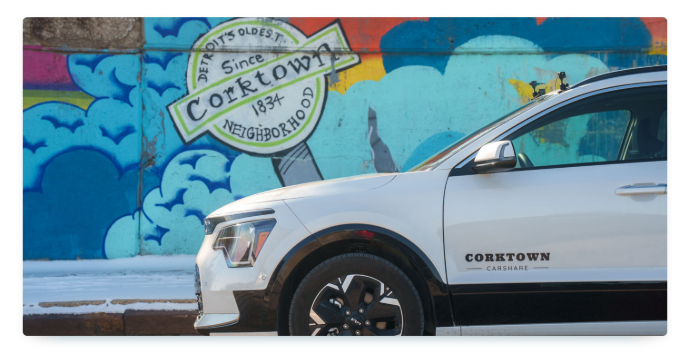 The front of a silver remote-controlled sharing car in front of a colorful wall in Corktown, Detroitw