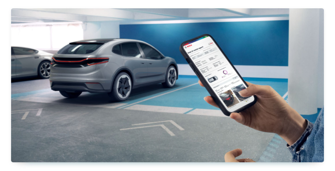 A person holds a smartphone with the Bosch RideCare app in front of a car in a parking garage
