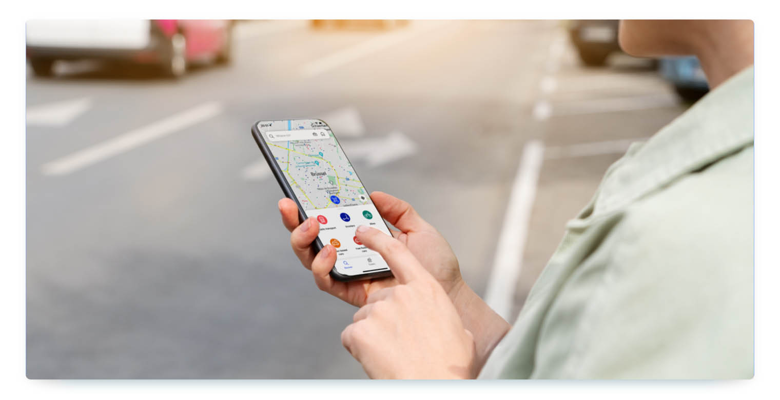 A person stands at a street and books a shared vehicle on his or her smartphone